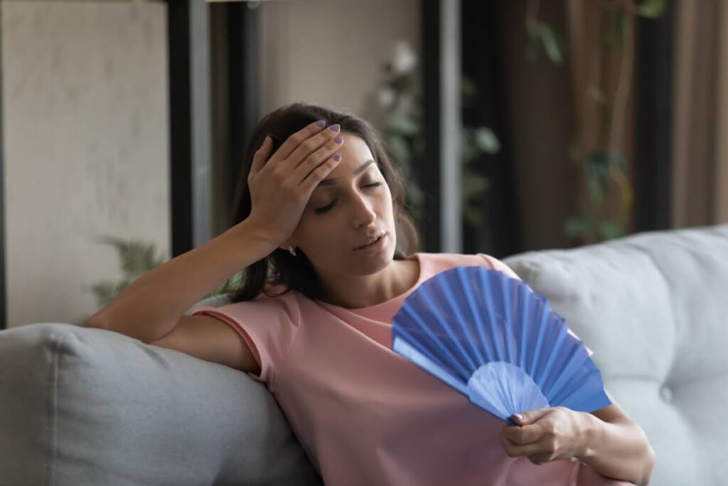 A woman fanning herself on a couch.