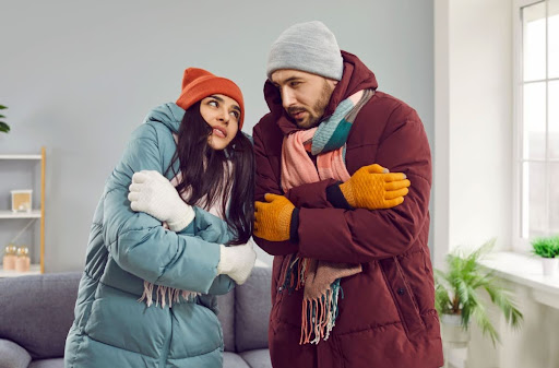 Warmly dressed man and woman trying to warm up at home.