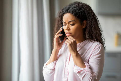 A concerned woman talking on the phone in a home.