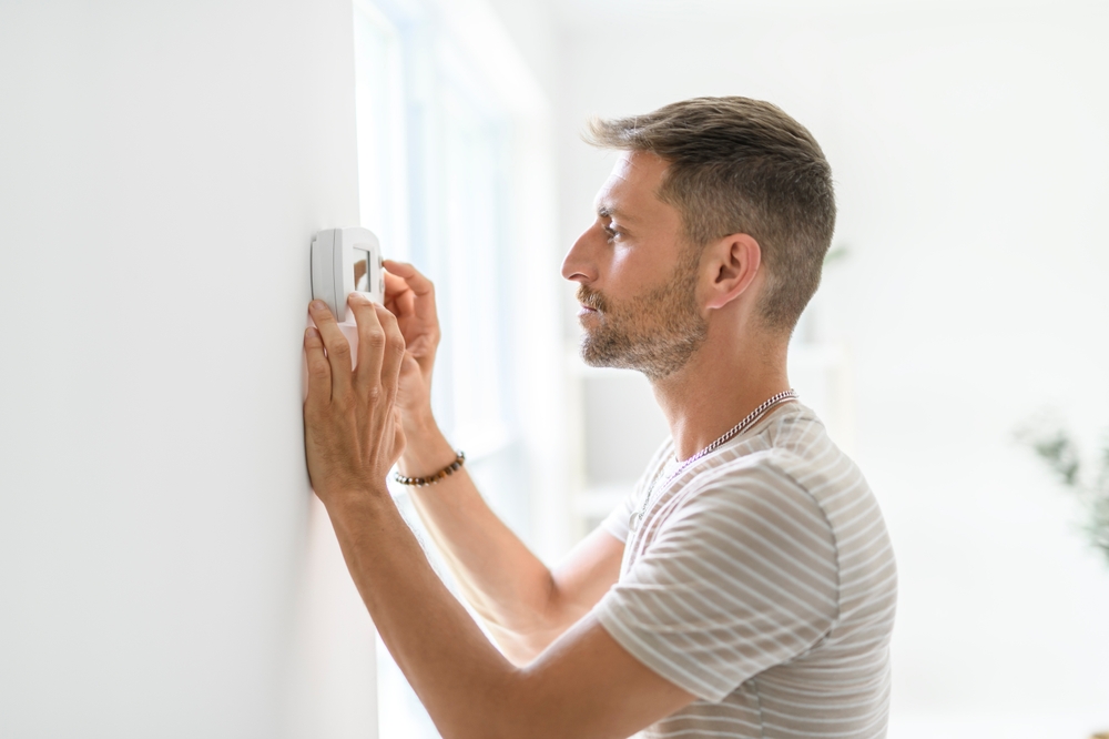 a man adjusting his thermostat, trying to figure out why his AC keeps short cycling